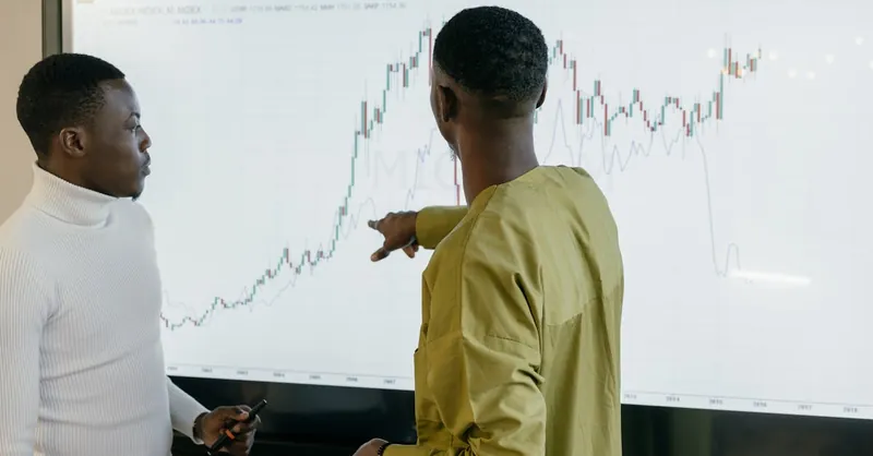 Two professionals discussing financial trends on a graph at the office.