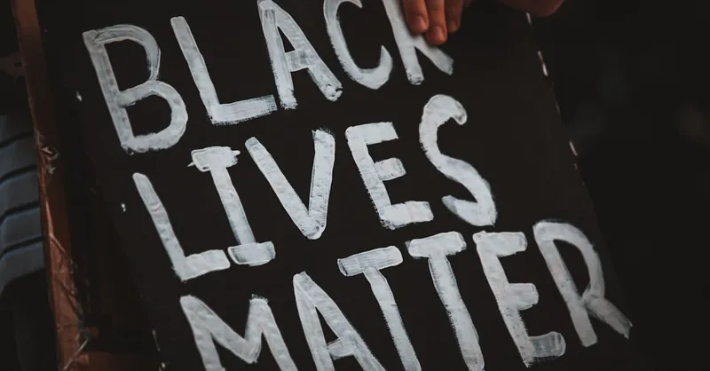 Crop unrecognizable social justice warrior behind placard with Black Lives Matter inscription in darkness