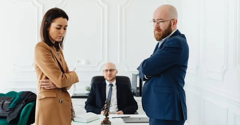 A couple in corporate attire seeks mediation during a business disagreement in an office setting.