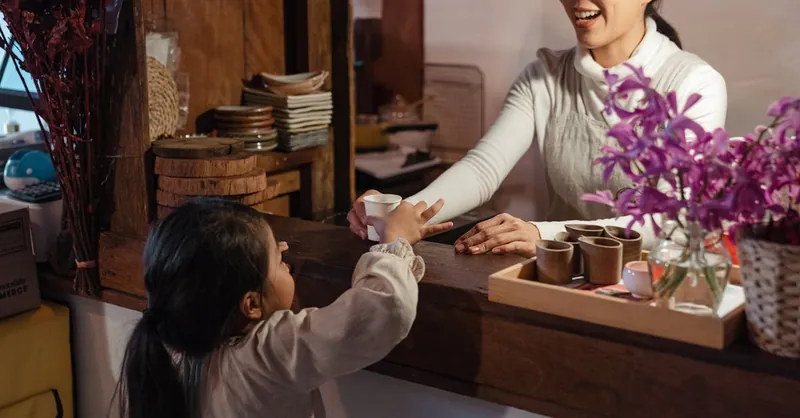 A warm interaction between a barista and a child at a cozy cafe counter.