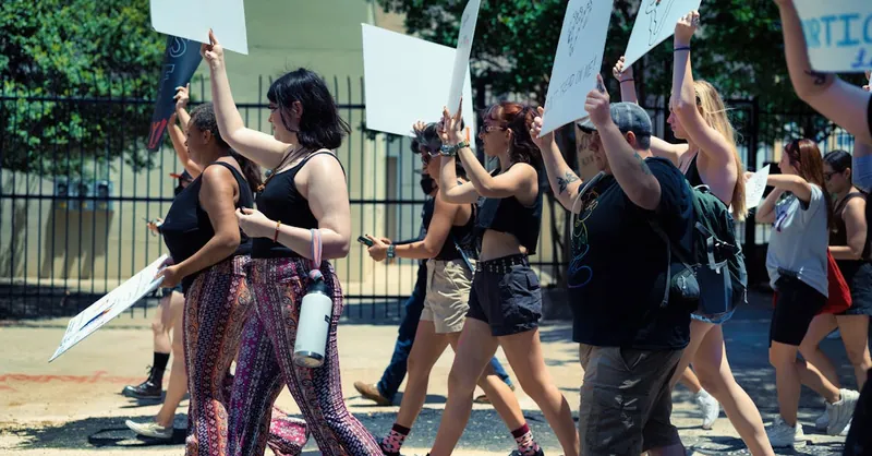 A diverse group of activists protesting outdoors, holding placards and engaging in social activism.