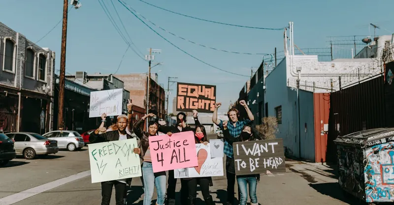 Diverse group of people holding signs advocating for equal rights during a peaceful protest outdoors.