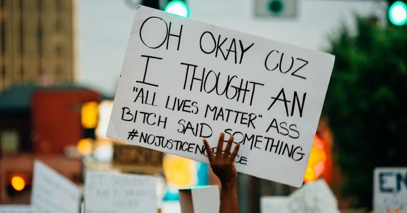 Protestor holds sign advocating social justice at dusk rally, emphasizing equality.