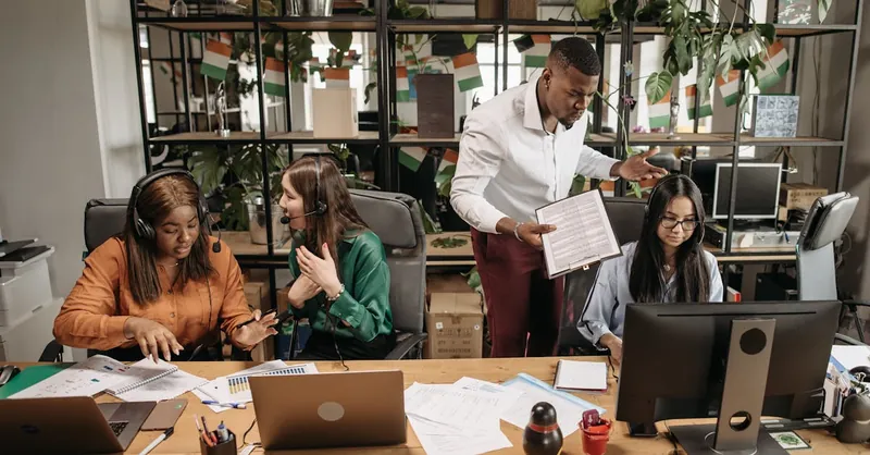 A diverse team of call center agents in a lively office setting, collaborating on tasks and discussing reports.