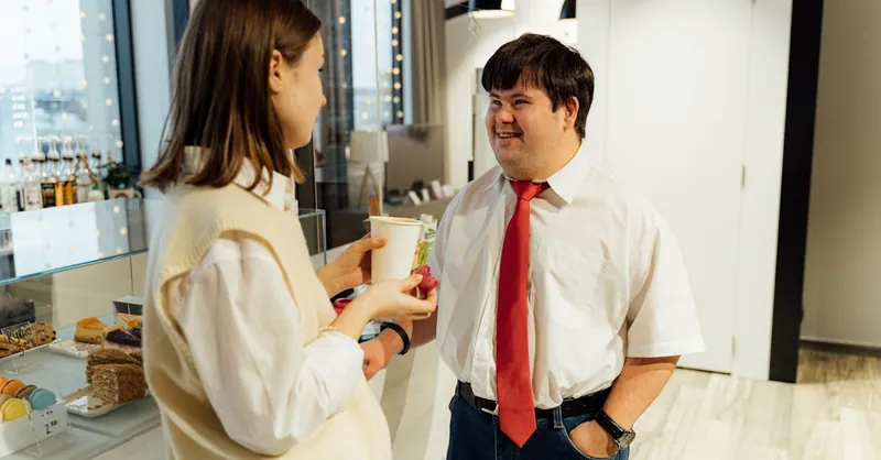 Professional staff and customer engaging in warm conversation inside a contemporary café.