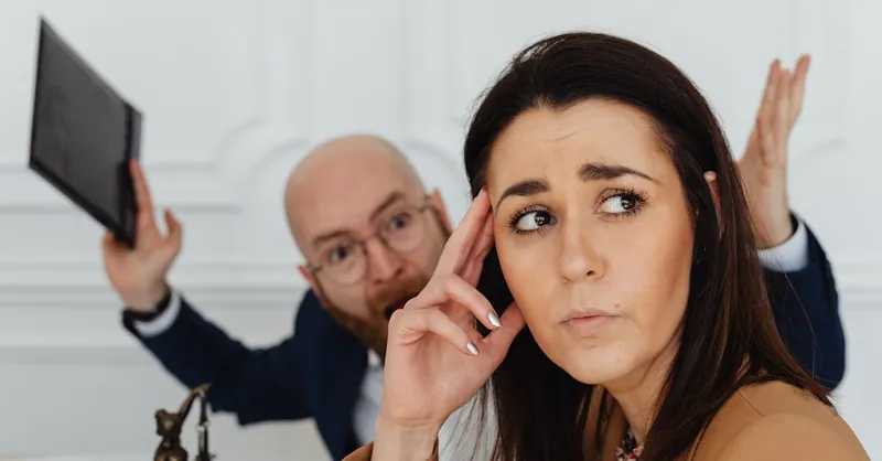 Two colleagues in a tense office situation, expressing frustration and concern.