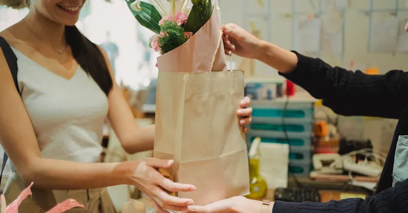 Smiling customer receiving a floral bouquet at a flower shop.