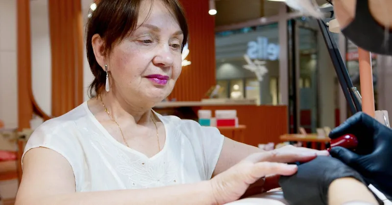 An elderly woman enjoys a relaxing manicure in a modern salon environment.