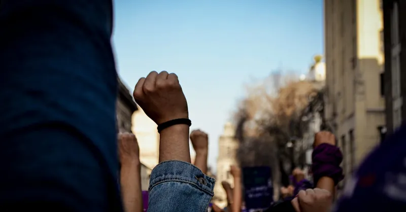 Vivid scene of women raising fists at an outdoor rally, symbolizing empowerment and rights advocacy.