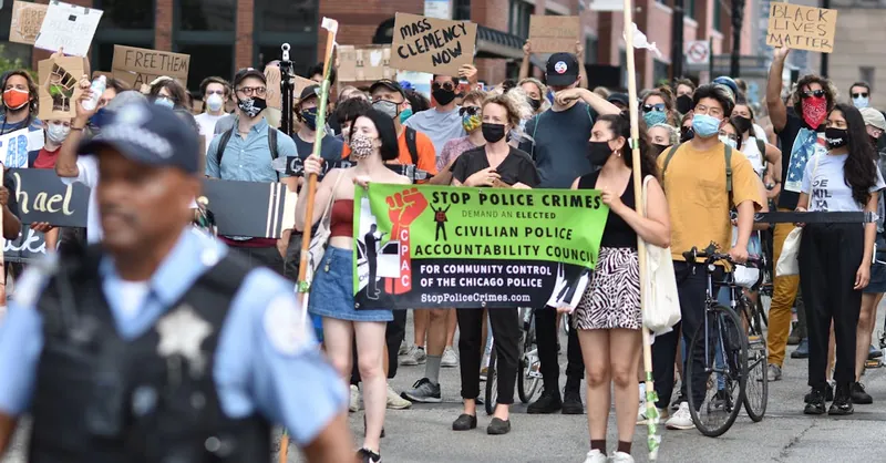Protesters march in Chicago demanding police accountability. Diverse crowd carries signs for justice.