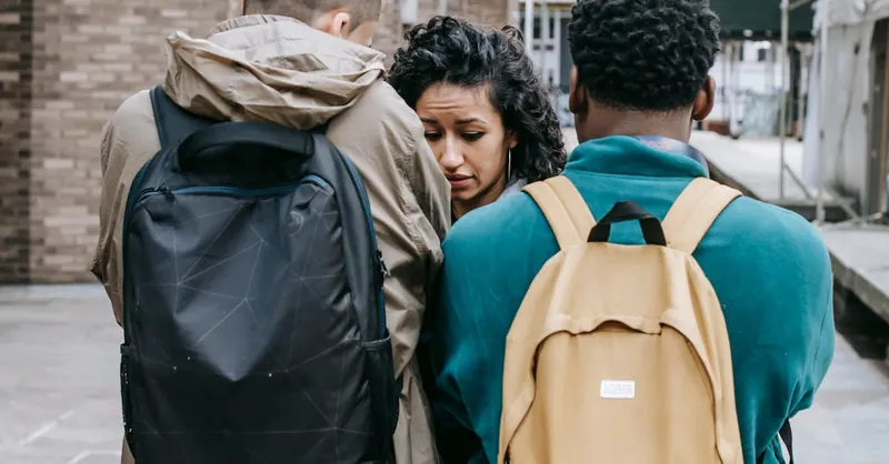 A tense interaction between diverse university students outdoors, showcasing conflict and emotion.