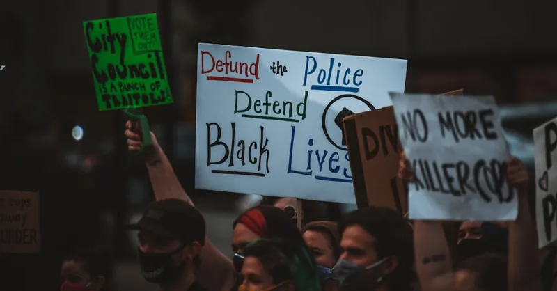 Crowd of unrecognizable social justice warriors in masks raising placards with titles while fighting for equality during COVID 19 pandemic
