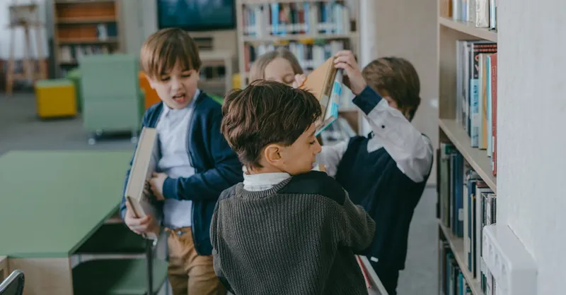 Children engaging in a playful conflict in a school library setting.