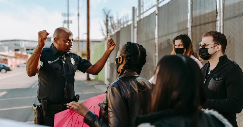 A diverse group of people engaging with a police officer during a street protest, highlighting activism.