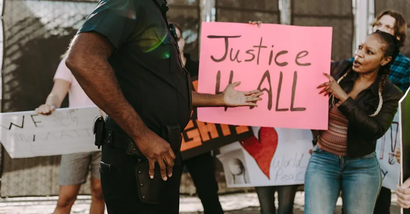 Diverse group holding signs for justice at a peaceful protest involving police.