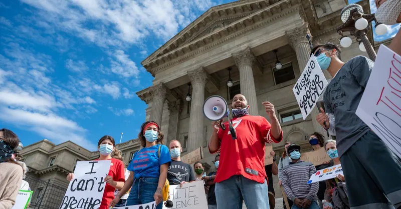 Protesters advocating for racial justice with signs and masks outdoors.