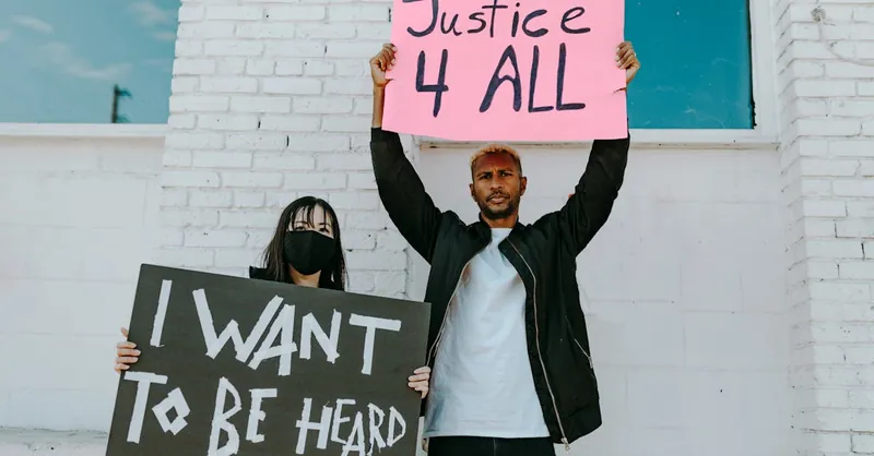 A diverse group of protesters holding banners advocating for justice and equality.