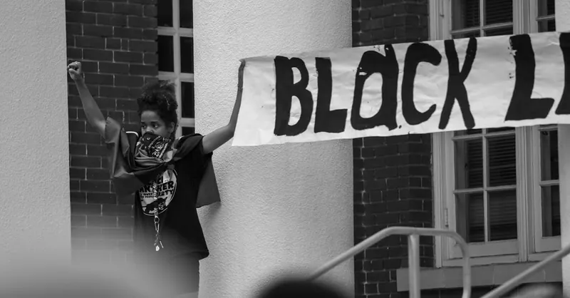 A powerful Black Lives Matter protest scene with a woman holding a sign, advocating for racial justice.