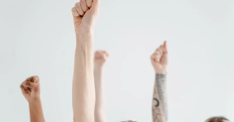 Dynamic image of diverse raised fists symbolizing empowerment against a white background.