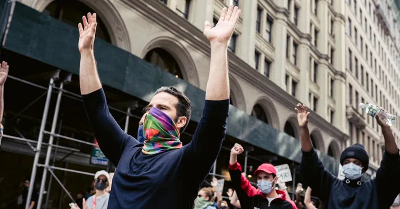 A group of masked protesters raising their arms during a city demonstration advocating for social justice.