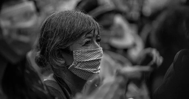 Black and white side view of unrecognizable elderly female in mask during manifestation on city street
