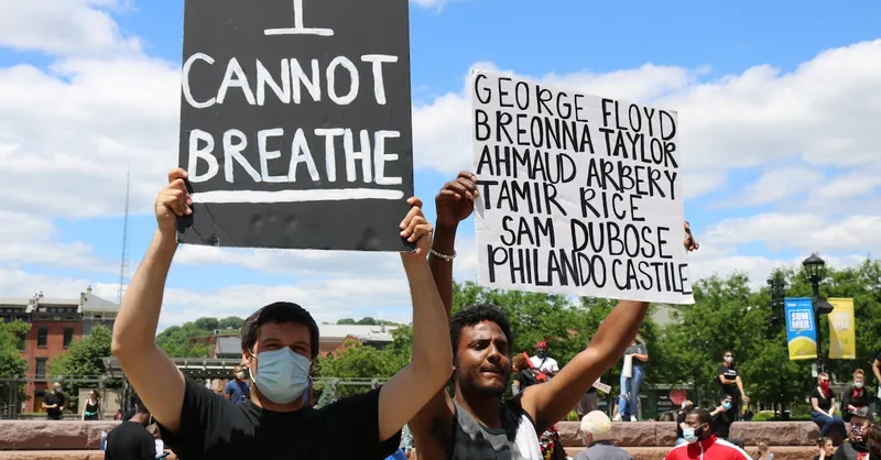 Protesters with signs rally for justice, highlighting victims of racial injustice.